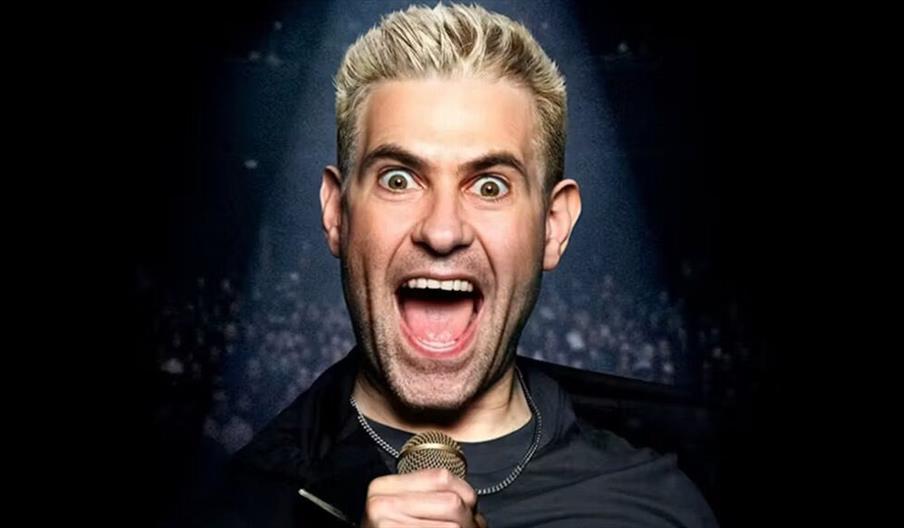 Promotional image for comedian Simon Brodkin's "Unleashed" stand-up tour, showing him excitedly holding a microphone, with bold yellow text featuring
