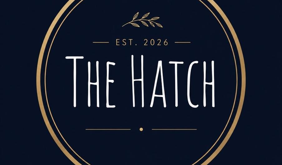 A dark circular logo with gold outline features the text "The Hatch" in large white letters, "EST. 2026" above it, and a small gold branch with leaves