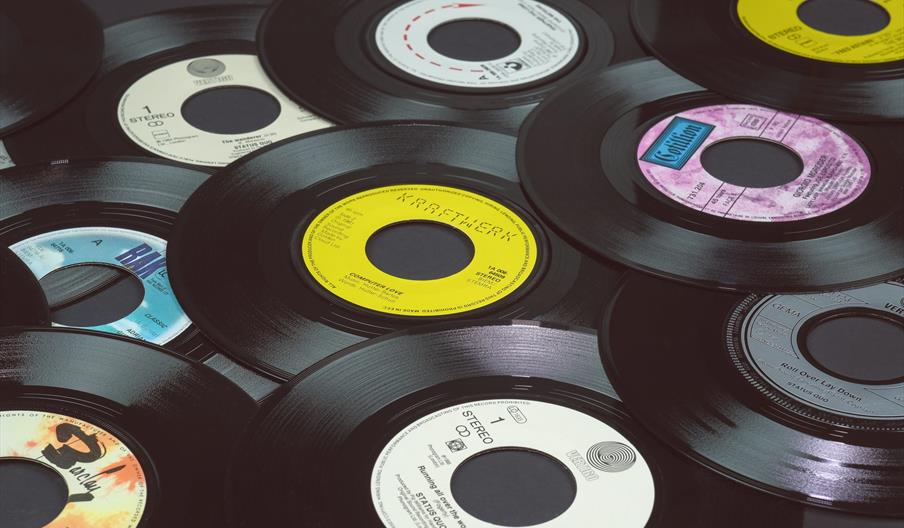 Several black vinyl 45 RPM records with colorful center labels are arranged in a close, overlapping pattern.