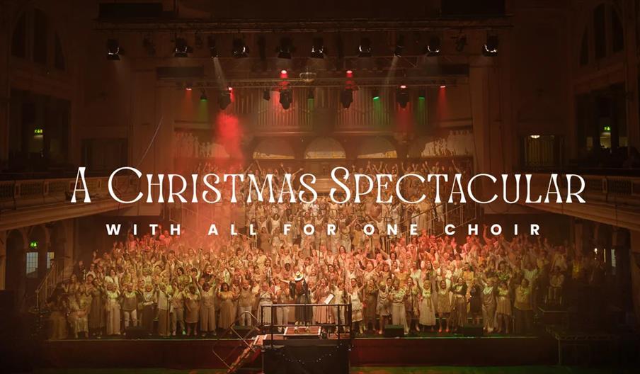 A large choir dressed in light-colored outfits performs onstage in a grand concert hall, with stage lights and colored fog, as text over the image rea