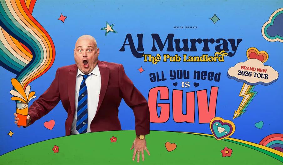 Al Murray in a maroon suit and striped tie stands with a surprised expression, holding a pint with colorful rainbow swirls, against a bright, cartoon-