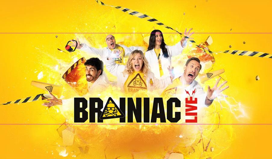 Five people in white lab coats stand in front of a bright yellow explosive background with caution tape and debris, all making excited and surprised e