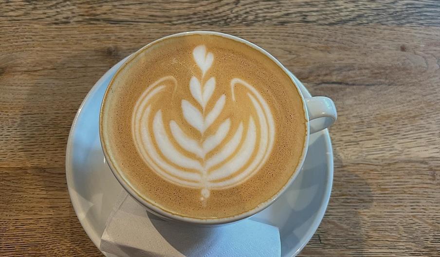 A latte with a flower pattern artwork on the foam.