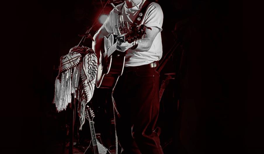 A promotional poster for a live music event features a black and white photo of a musician playing guitar and singing into a microphone on stage. The