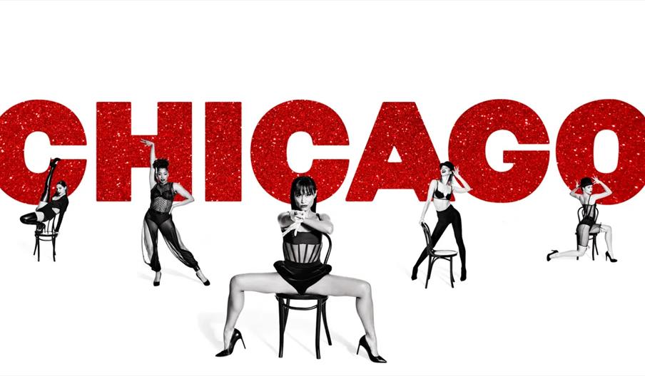 5 women in black and white pose in front of the word Chicago in a big red sparkly font.