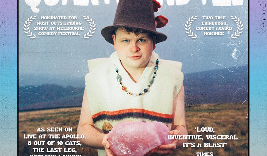 A promotional poster for Dan Tiernan's comedy show "Quartz and All" features Dan wearing a tall, pointed hat and a poncho, holding a large piece of pi