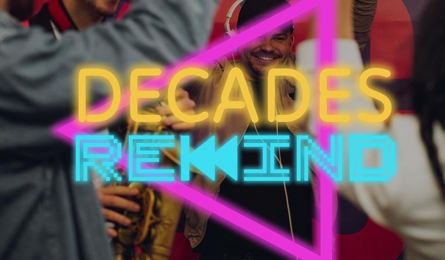 A group of people cheer and celebrate at a party, with one person holding a saxophone and another wearing headphones. The words "DECADES REWIND" are d