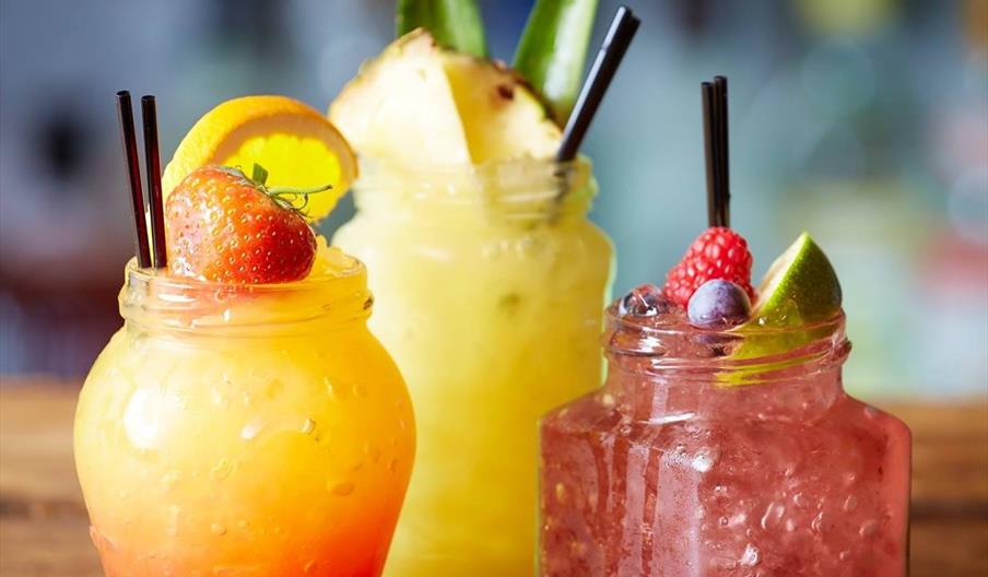 3 cocktails in difference shaped glasses with fresh fruit in them.