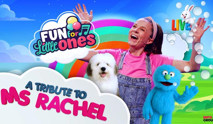 A smiling woman in a pink shirt and denim overalls poses with her arms raised, next to a fluffy white dog and a blue puppet in a colorful, cartoon lan