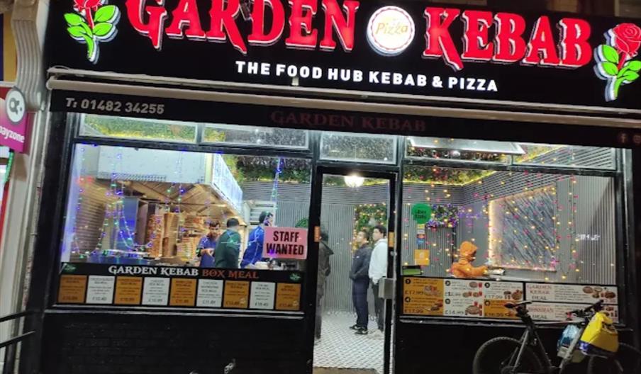 The shopfront of Garden Kebab, with a bright red and black sign featuring roses either side.