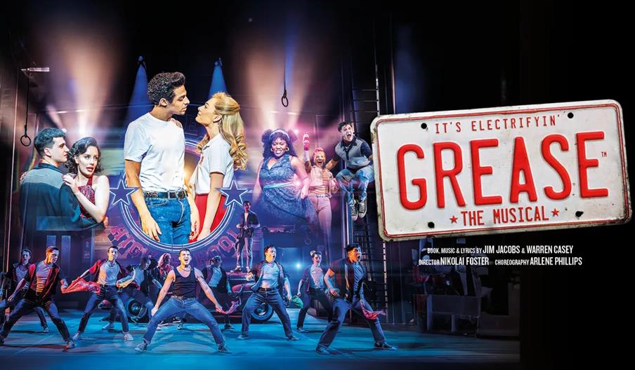 Promotional image for "Grease The Musical" featuring a group of performers in 1950s-style costumes dancing and singing on stage, with a large license