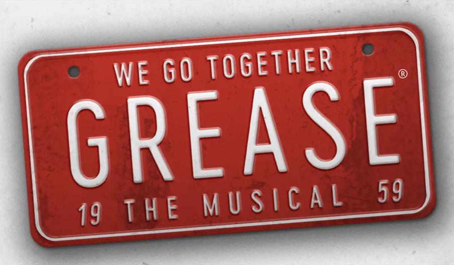 A red vintage-style license plate with white letters reads "We go together GREASE 19 The Musical 59."