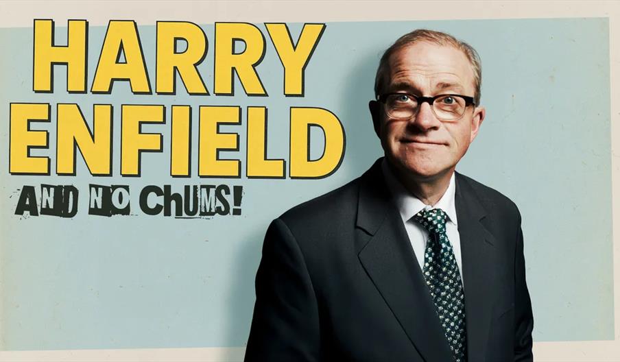 Harry Enfield in a suit and patterned tie stands in front of a blue background with large yellow text reading "Harry Enfield and No Chums!"