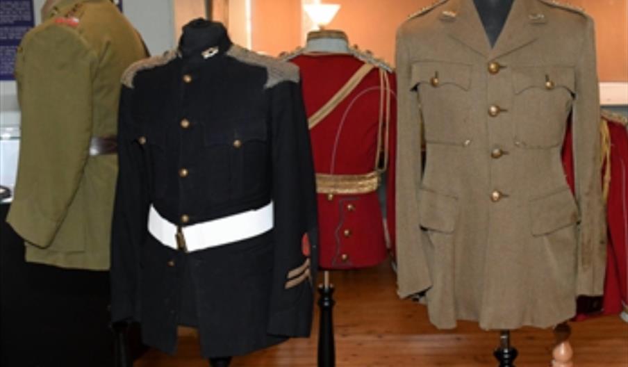 Interior of Burton Constable Hall, Four military uniforms from different eras and branches are displayed on headless mannequins in a museum setting, i