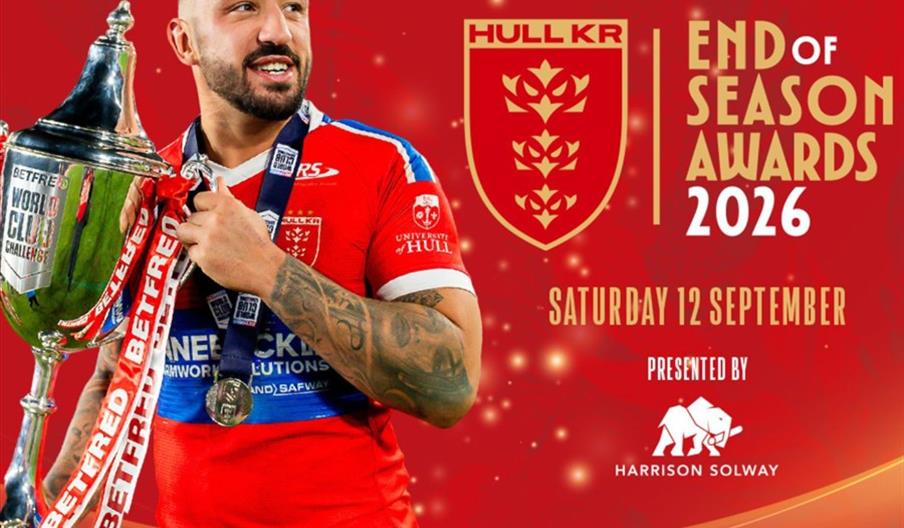 A rugby player in a red Hull KR jersey holds a large trophy and smiles, standing in front of a red background with the Hull KR crest and text promotin