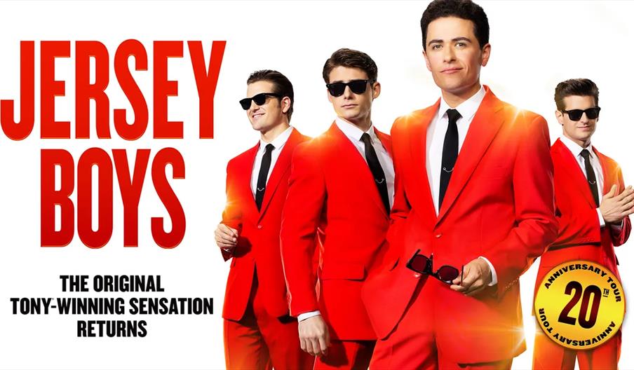 Four men in matching bright red suits, white shirts, black ties, and sunglasses stand confidently in a promotional image for "Jersey Boys," with large