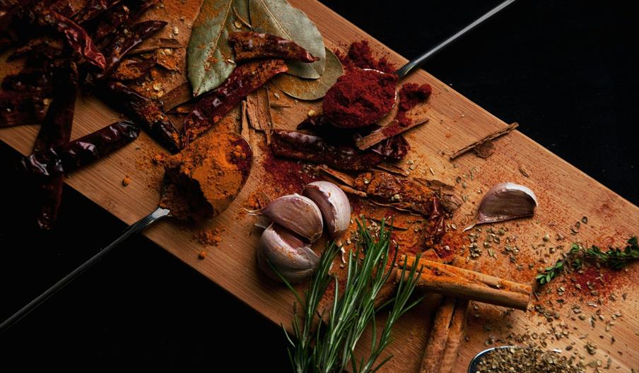 A wooden board covered in various spices, chilis and herbs.
