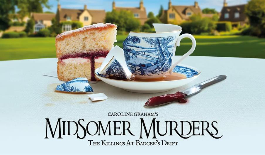 A broken blue and white teacup with spilled tea and fragments sits beside a slice of layered sponge cake and a knife smeared with red jam on a table,