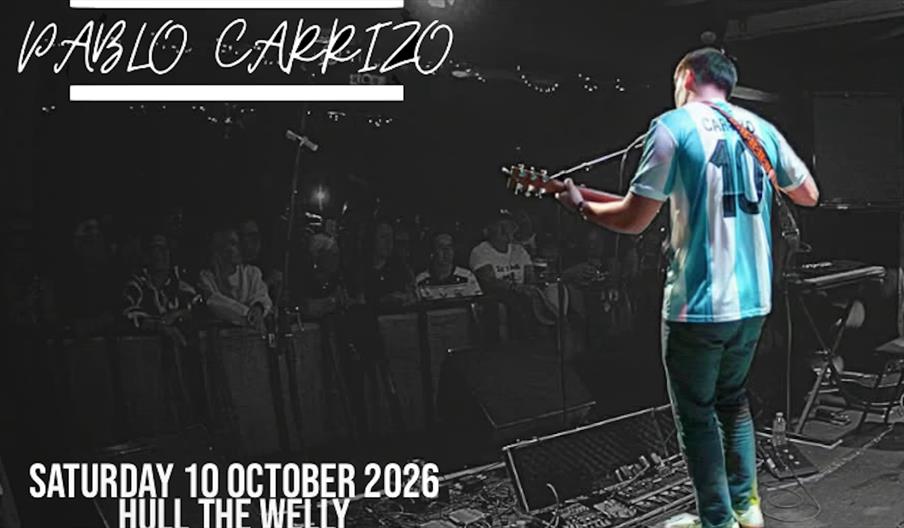 A musician wearing an Argentina soccer jersey and holding a guitar performs on stage to a seated audience in a dimly lit venue. Text at the top says "