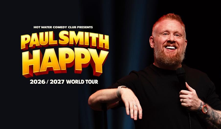 A smiling man with a beard holds a microphone on stage next to large bold text that reads "Paul Smith Happy 2026/2027 World Tour" with "Hot Water Come