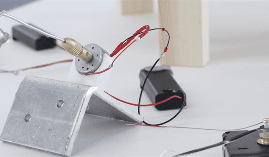 A series of electronics connected to 2 small bells.
