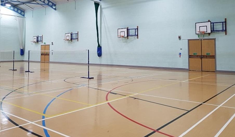 The interior of The Waudby Centre, a sports hall with several basketball hoops and badminton nets set up.