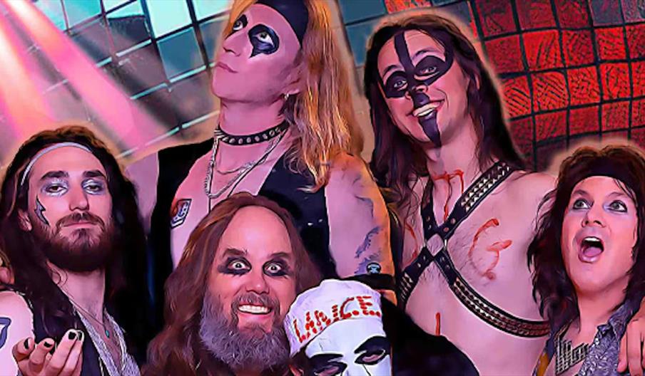 A group of six people dressed in glam rock or heavy metal costumes with dramatic face paint, long hair, and accessories, pose together in front of a c