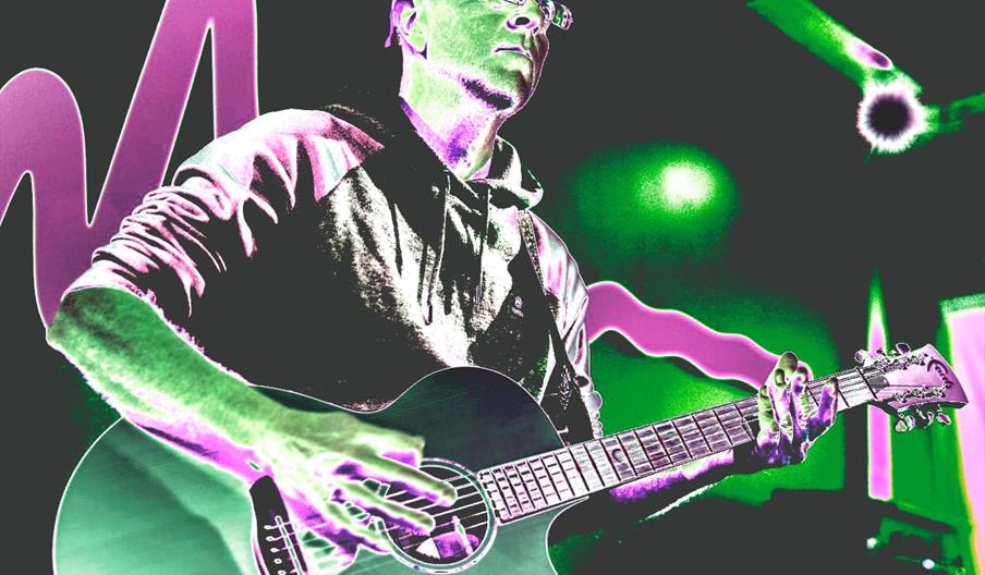 A stylized, neon-toned image of a person in a hoodie and cap playing an acoustic guitar, with vivid green and pink hues and abstract light shapes in t