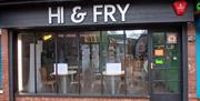 Street view of "HI & FRY" takeaway, with large glass windows showing tables and chairs inside; there is a water bowl on the pavement outside the entra