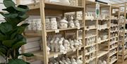 Shelves of blank ceramic pottery ready for painting at Cozy Kiln studio in Hull.