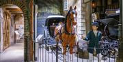 A mannequin of a man in victorian garb stands next to a horse and cart in a victorian streetscene from the Streetlife Museum.