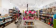 Interior of Lili and Milas. A brightly lit pet store featuring neatly organized shelves filled with treats, toys, and various pet supplies; a central
