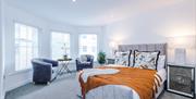 Stylish, large, bright bedroom with double bed, two grey armchairs.