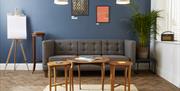Seating area with grey sofa, coffee tables and various wall art