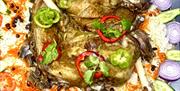 A large decorative platter filled with grilled meats, including kebabs, chicken, and lamb chops, served over a bed of seasoned rice with roasted tomat