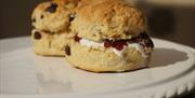 A plate with two scones, one filled with jam and cream.