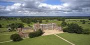 The exterior of Burton Constable Hall in Skirlaugh. It is a large stately home made of brickwork and white windows, with a view along the pathway lead