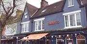 A blue Victorian-style building with pointed roofs and white trim houses "Garbutts," a bar and restaurant. The exterior is decorated with bunting and