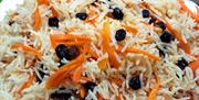 A bowl of white rice with raisins and slithers of carrot.