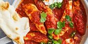 A dish of chicken curry in a tomato sauce with slices of green chilli.