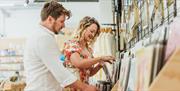 Two people browsing art prints and stationery displayed on a wall rack inside Form Shop and Studio, a creative retail space featured by Visit Hull.