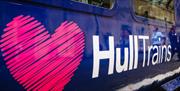 Close-up of a Hull Trains carriage featuring the company branding. A large pink heart-shaped logo and the white text “Hull Trains” are displayed on th