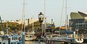 Historic Spur Lightship vessel moored among boats in Hull marina, with masts rising above the water and modern waterfront buildings in the background